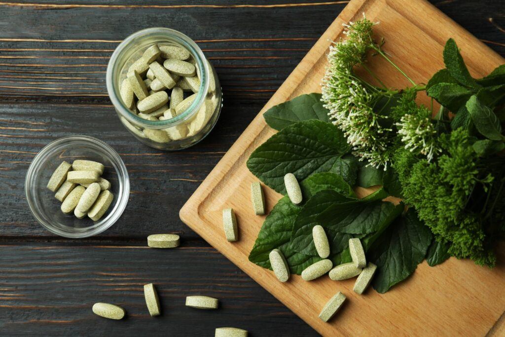Various herbal supplements and leaves on a wooden board, representing natural pancreatic health supplements.