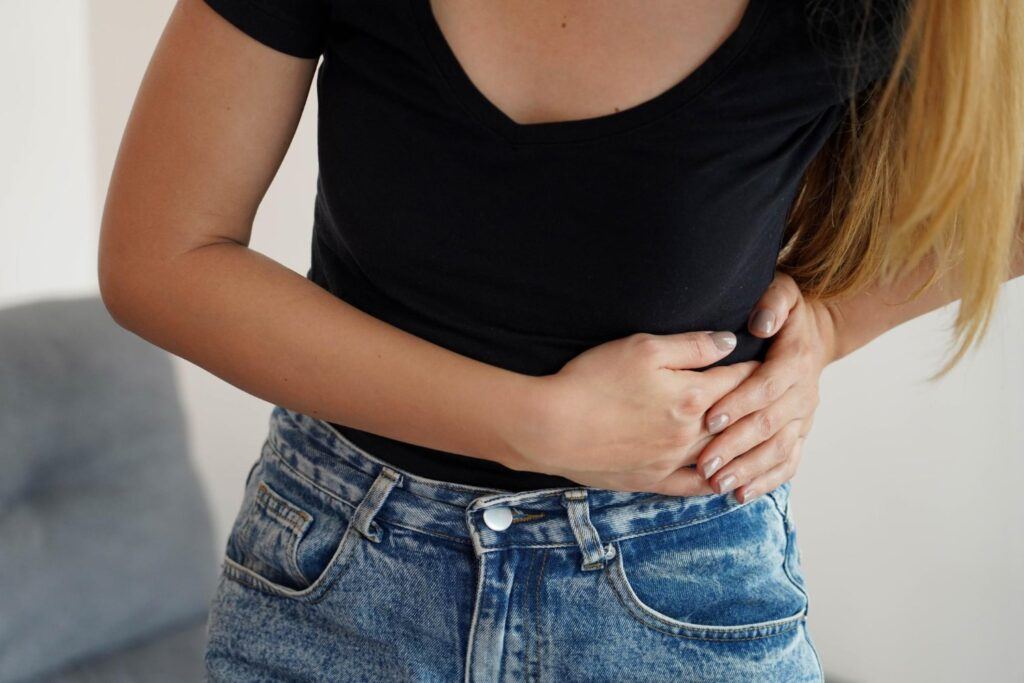 A person clutching their abdomen, experiencing pain related to pancreatic health issues.
